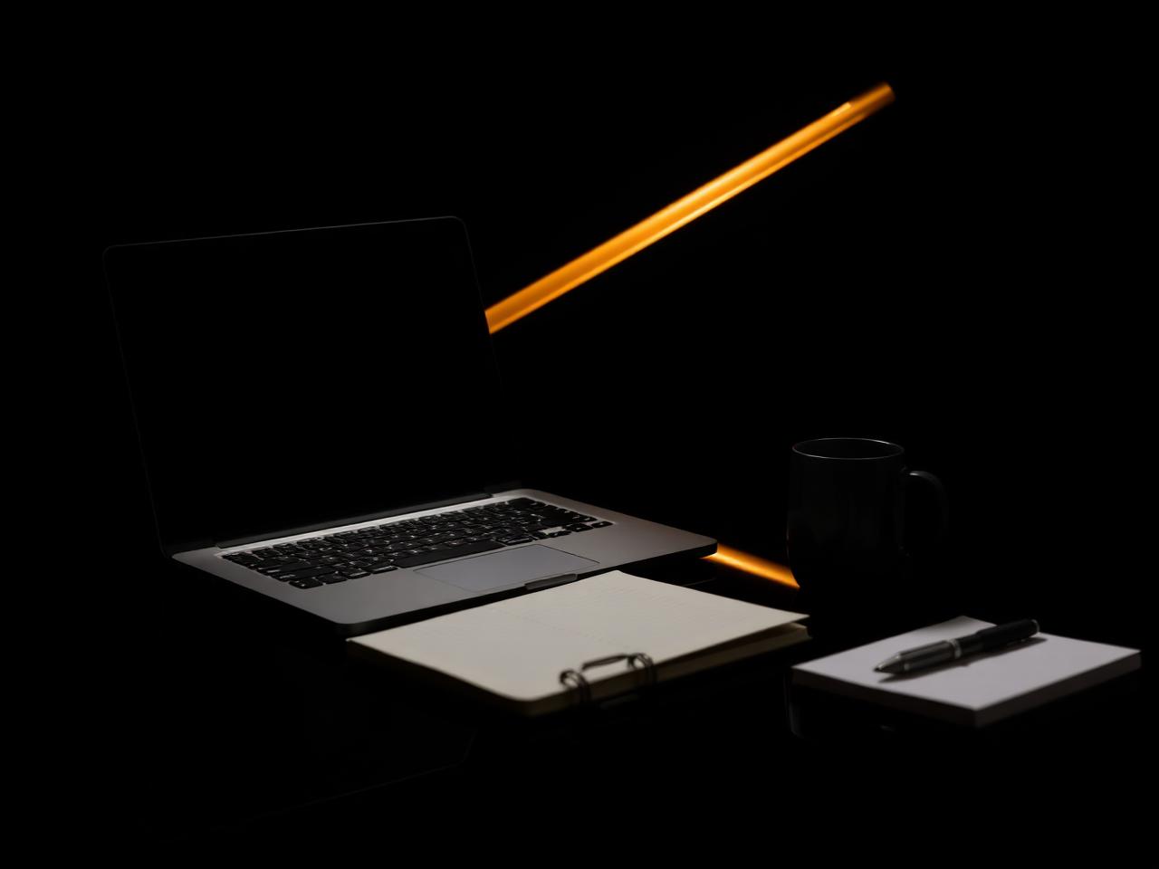 Laptop and notebook on a dark desk